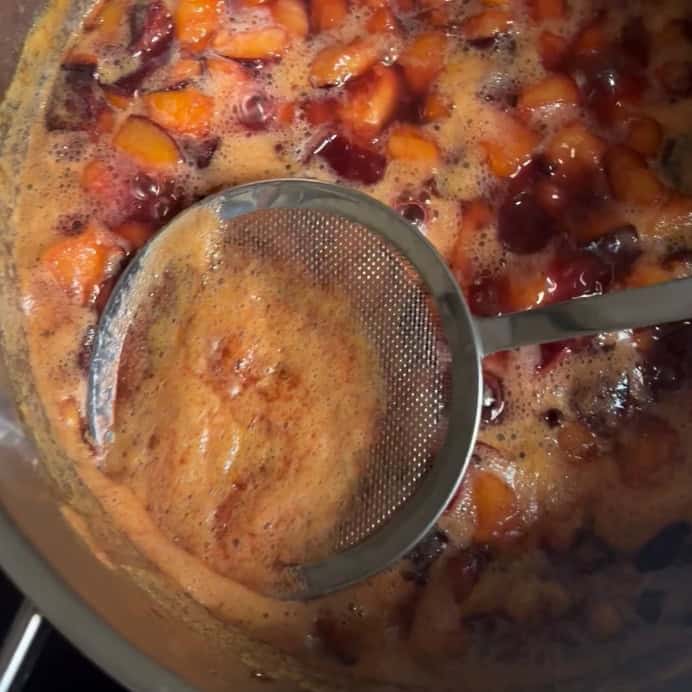 Skimming foam from the surface when cooking plums.