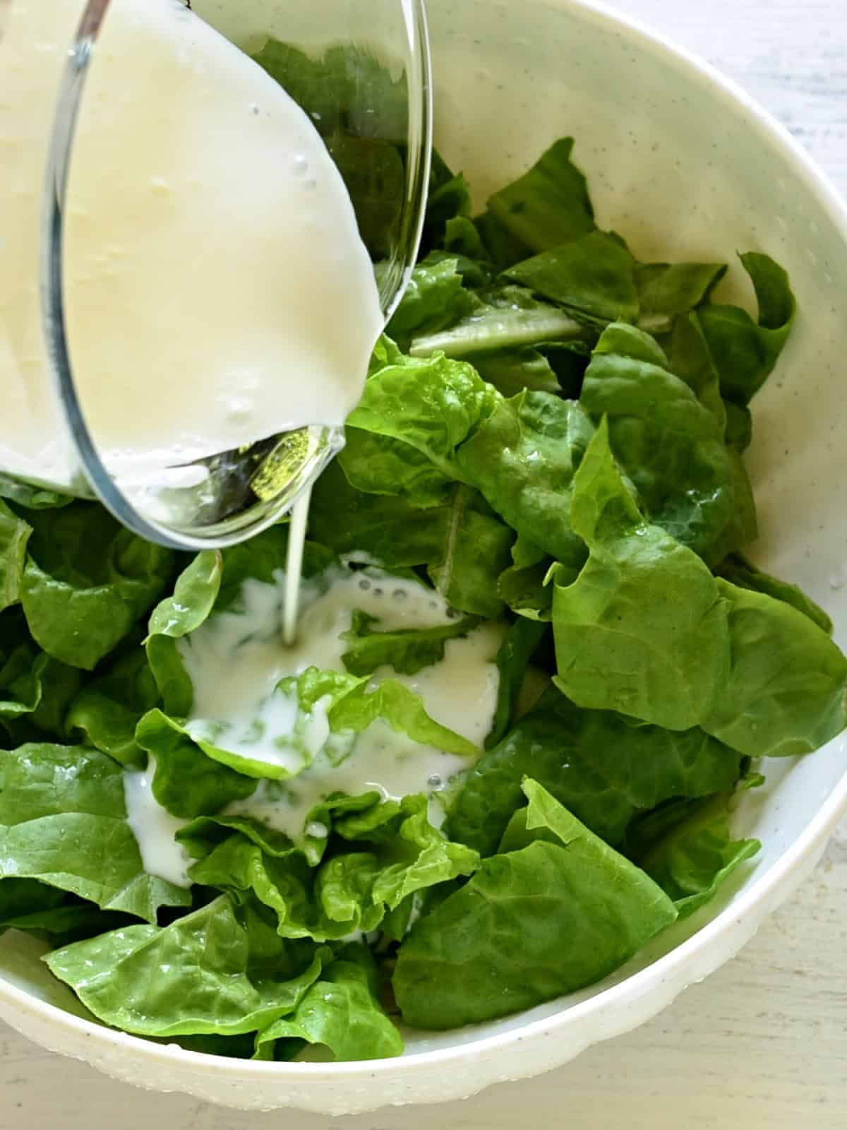 pouring dressing over lettuce leaves