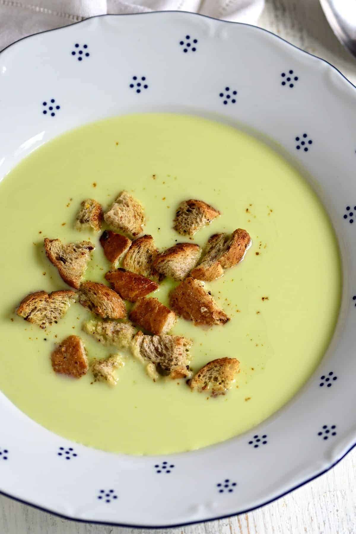 Frozen pea soup served with bread croutons in a bowl.
