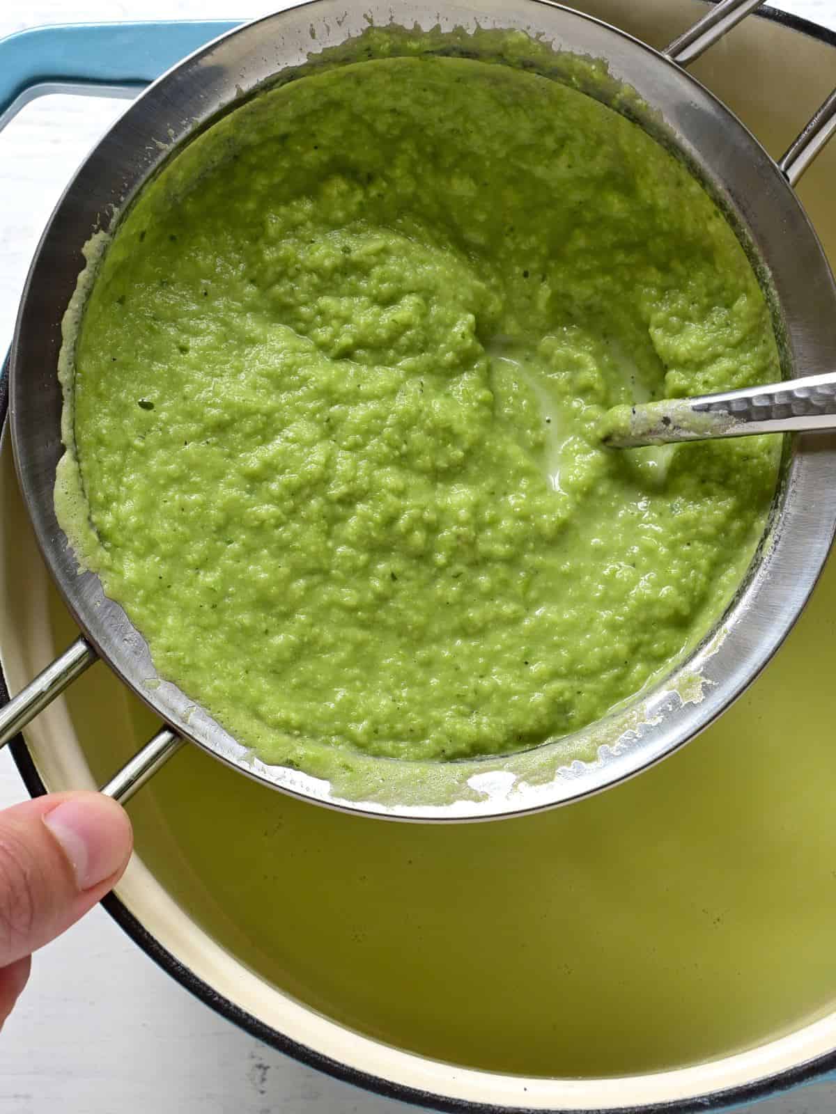 Straining pea soup through a sieve.