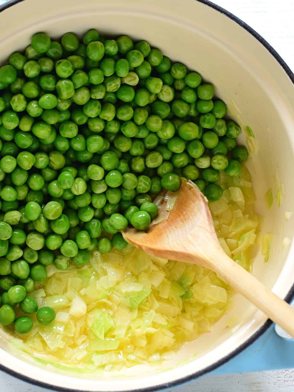 Adding frozen peas to the soup.