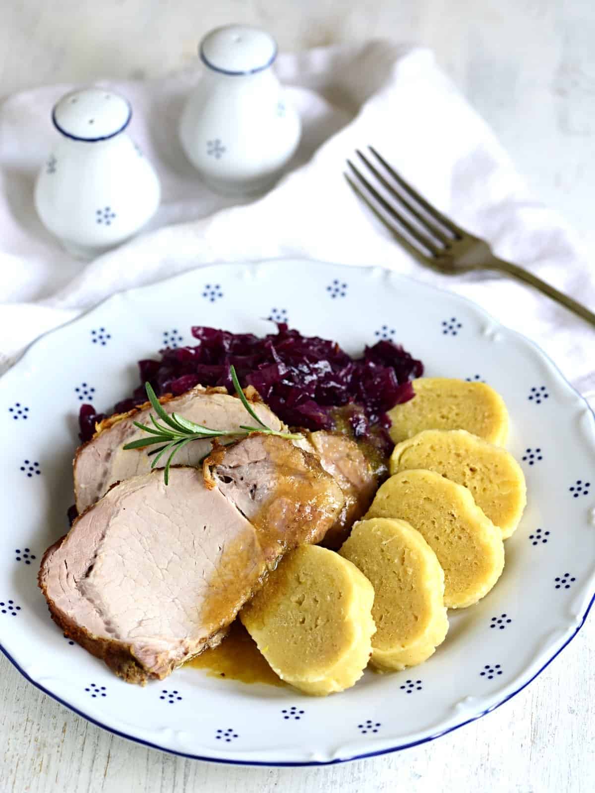 Roasted pork shoulder served with potato dumplings and red cabbage.