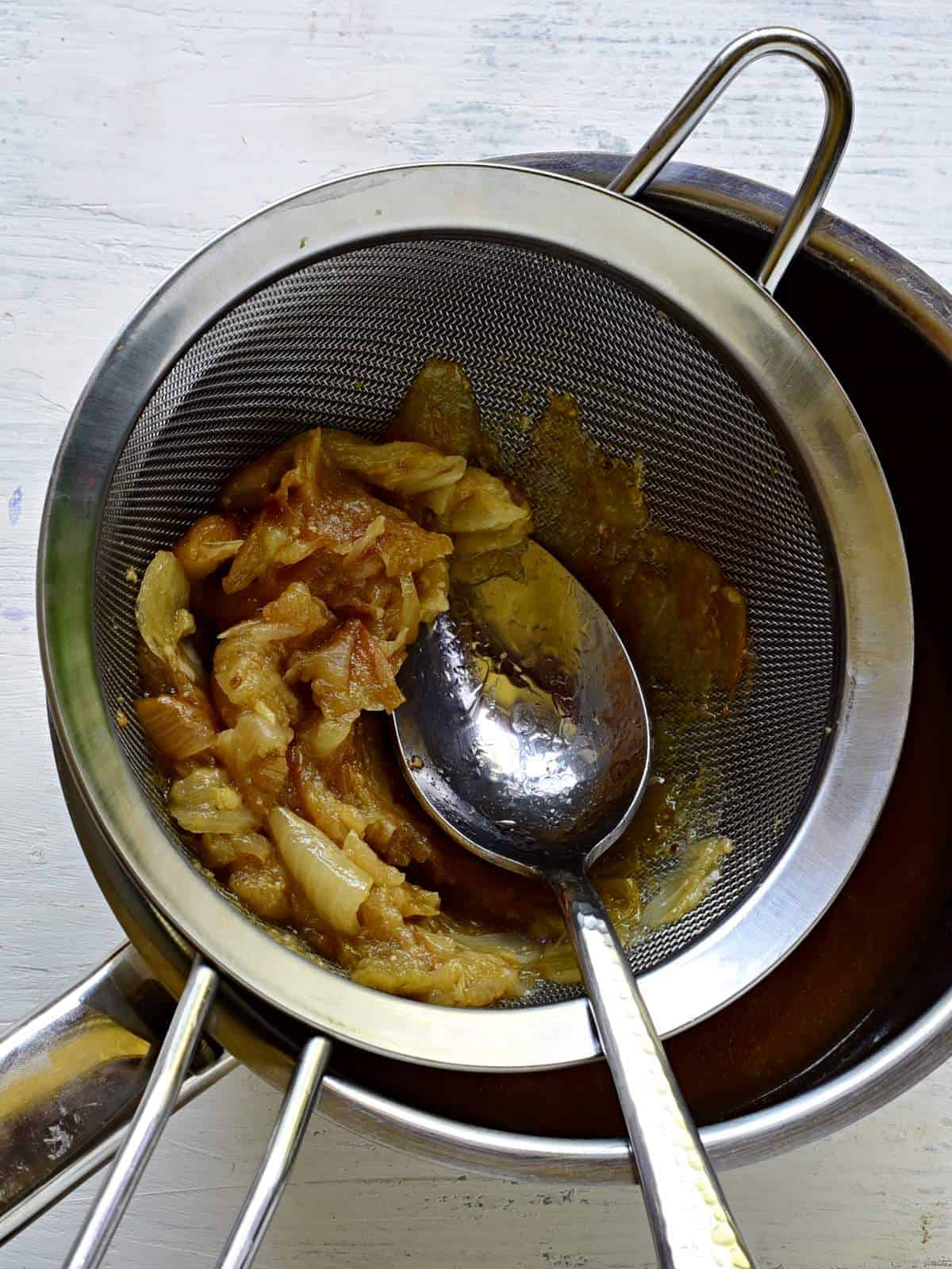 pressing onions throught a sieve.