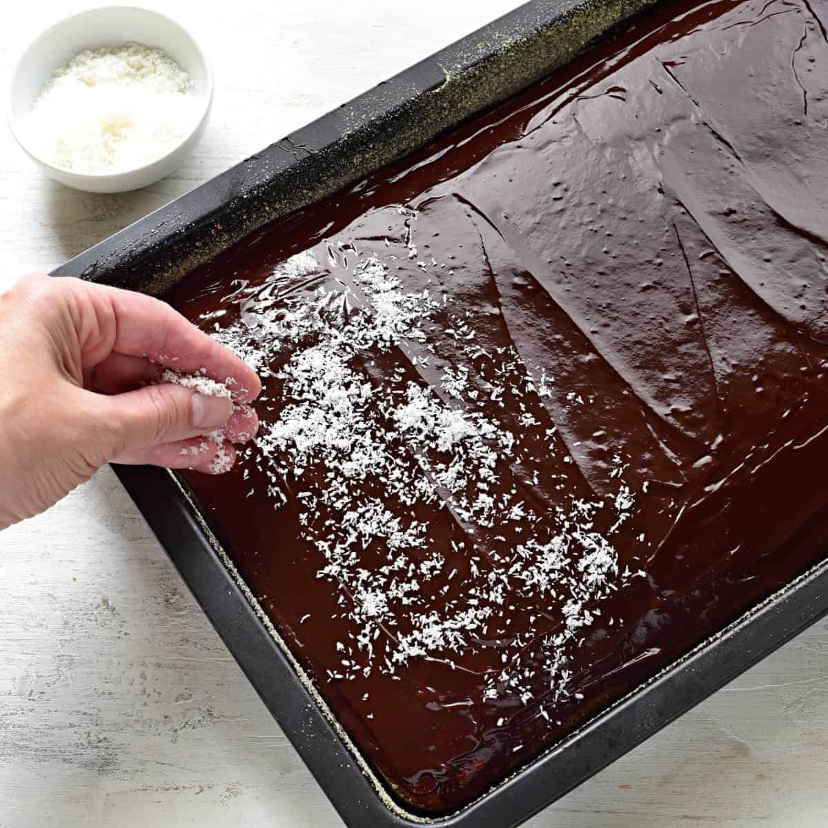 Sprinkling shredded coconut over a buttermilk cake.