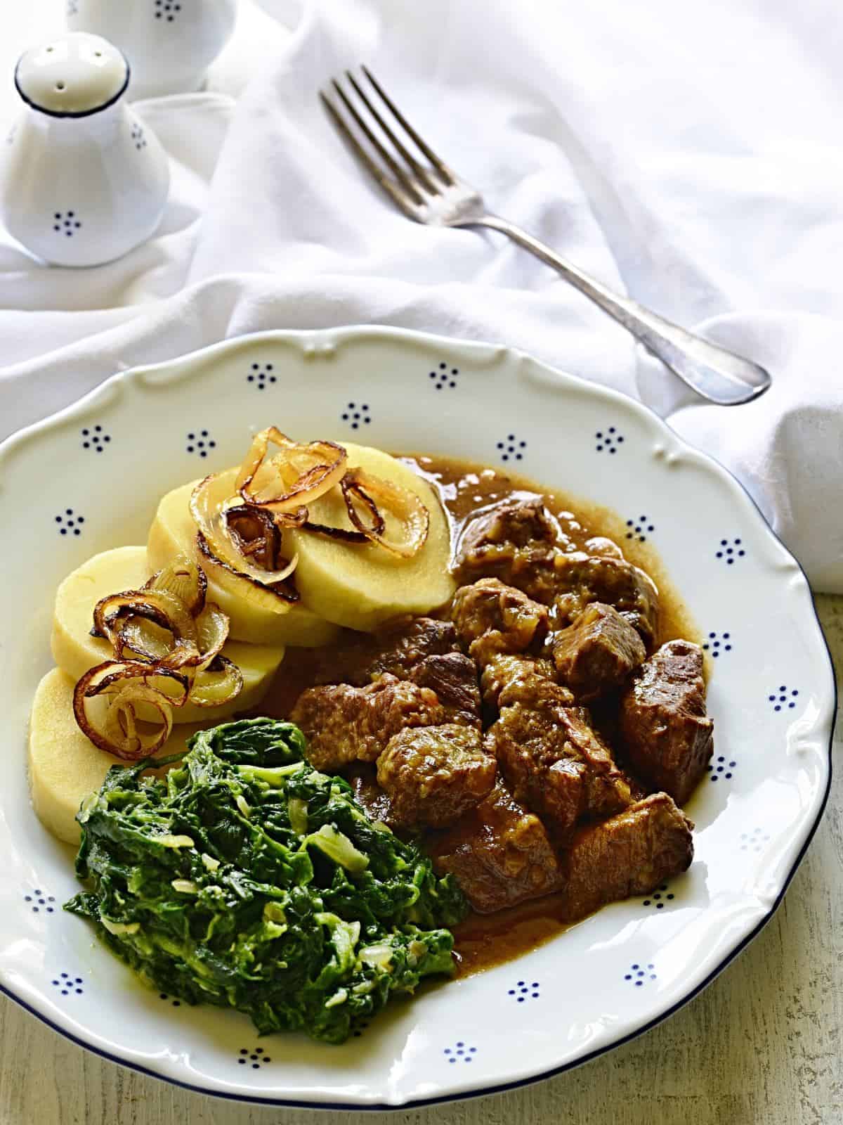 Beef cubes with garlic gravy, served with potato dumplings and spinach.