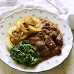 Garlic beef cubes served with potato dumplings and spinach, Czech hovězí na česneku dish.