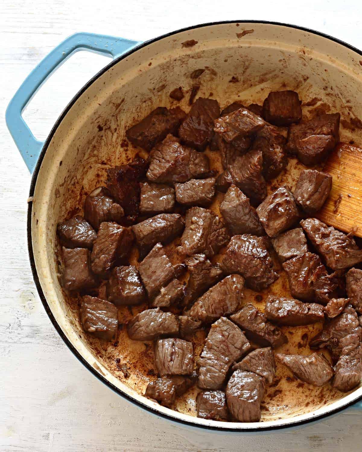 Searing beef cubes in a pan.