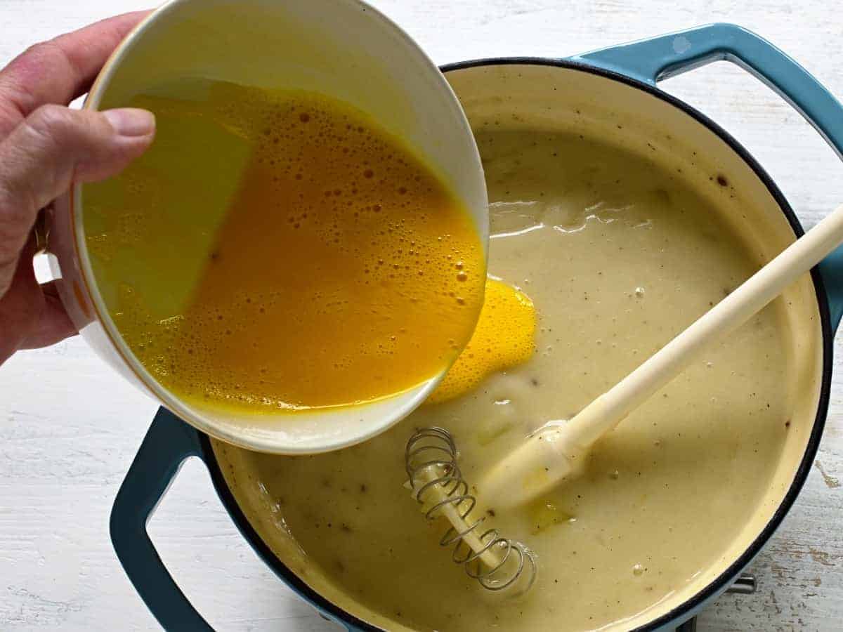 Pouring whisked eggs into sauce.