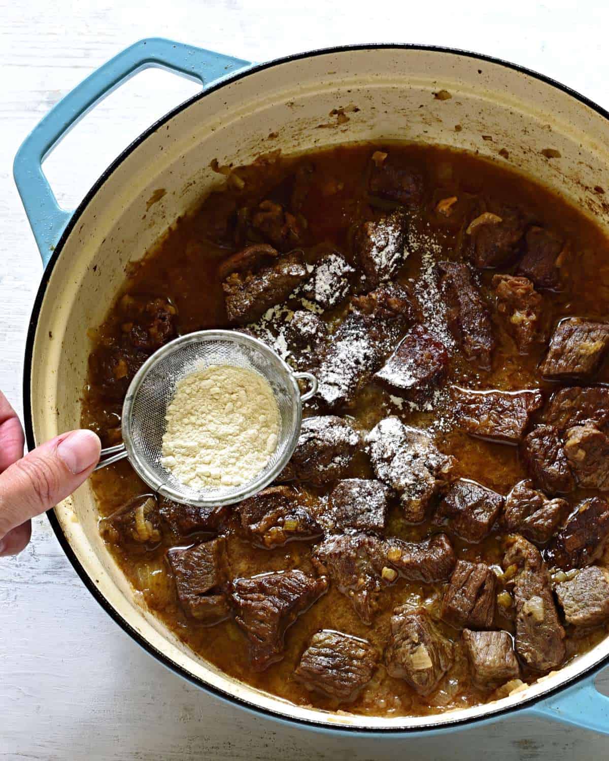Thickening the garlic gravy with beef cubes.