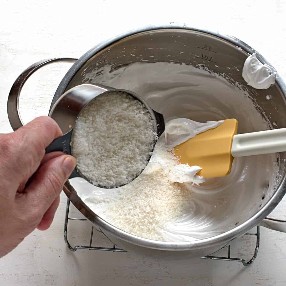 Pouring shredded coconut in meringue.