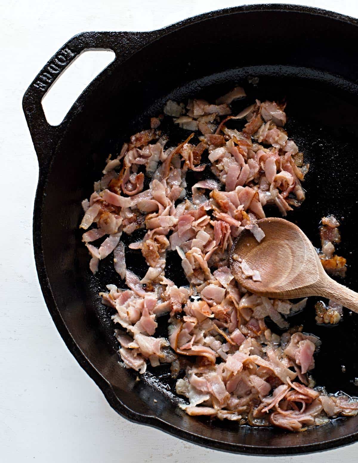 Frying bacon strips in a pan.
