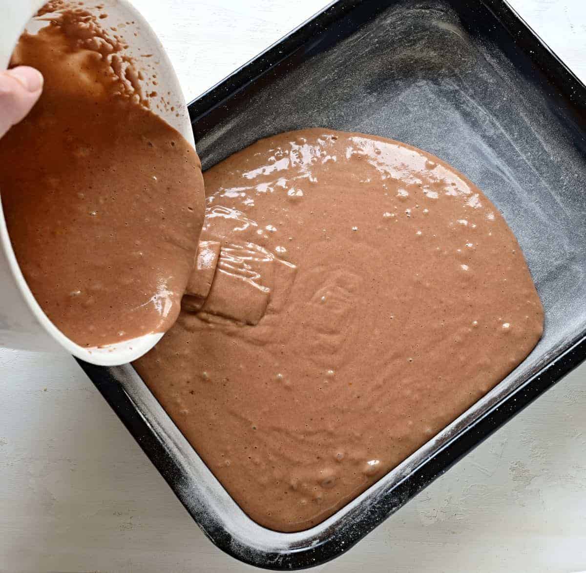 Pouring gingerbread batter in a sheet pan.