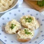 Garlic cheese spread on white bread roll slices.