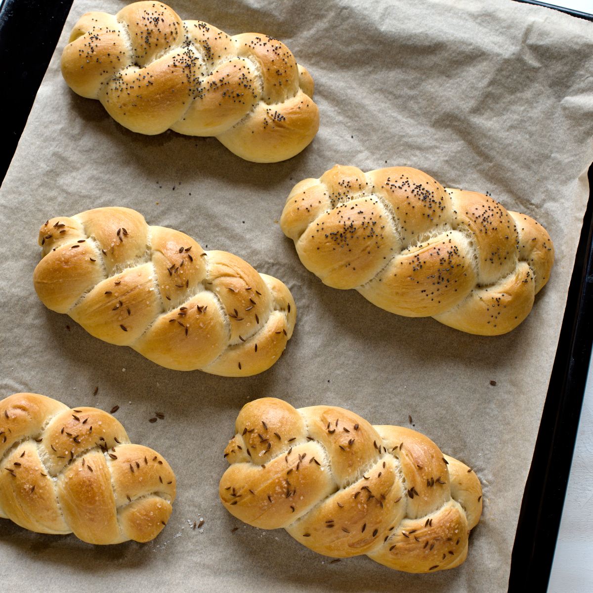 Baked bread rolls on a sheet lined with parchment paper. 