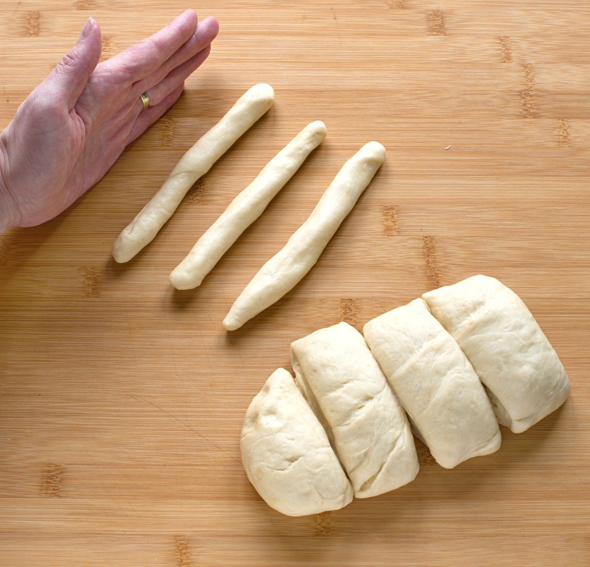 Three strands of yest dough on a wooden working surface, left a palm. 