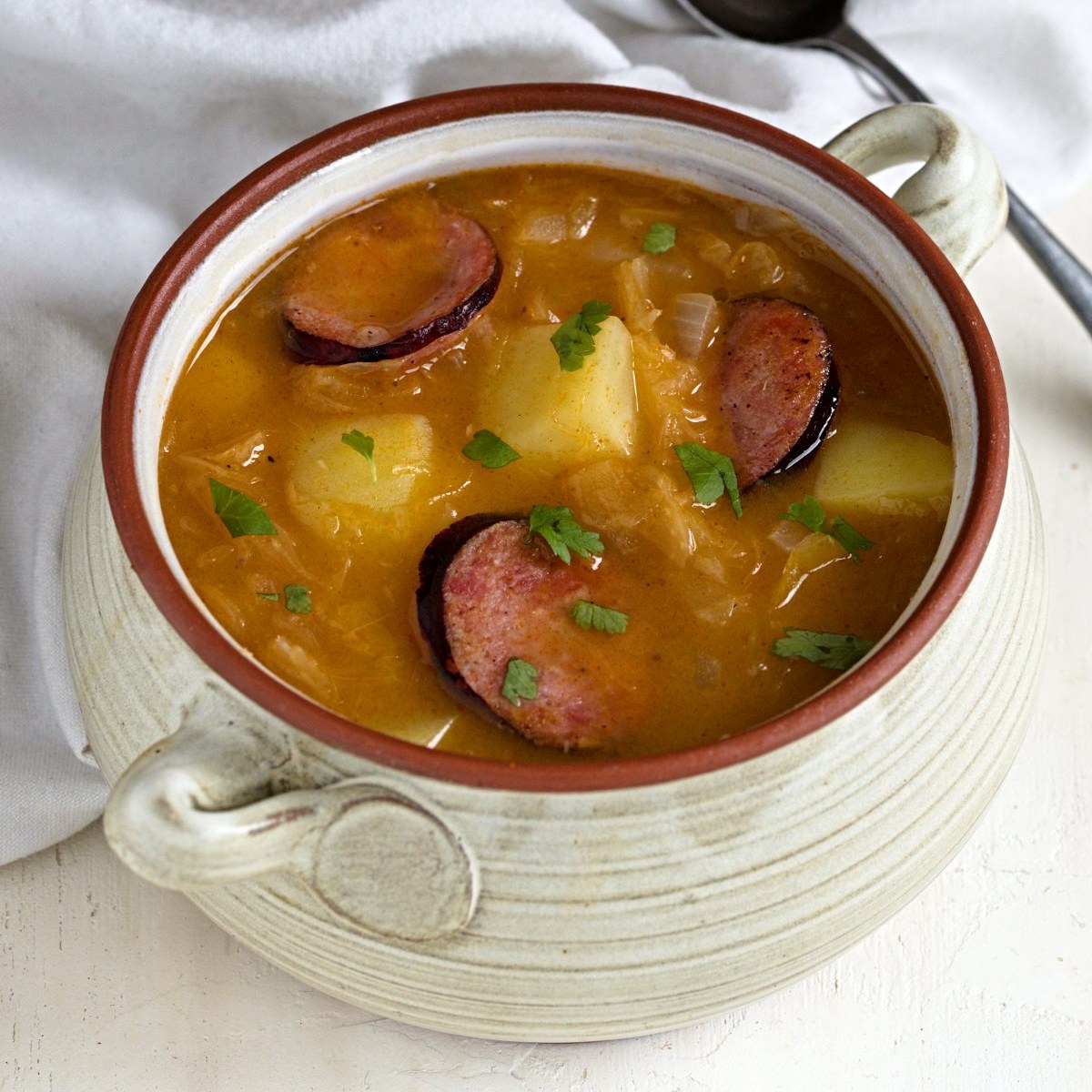 Czech sauerkraut soup with fried sausage served in a bowl.