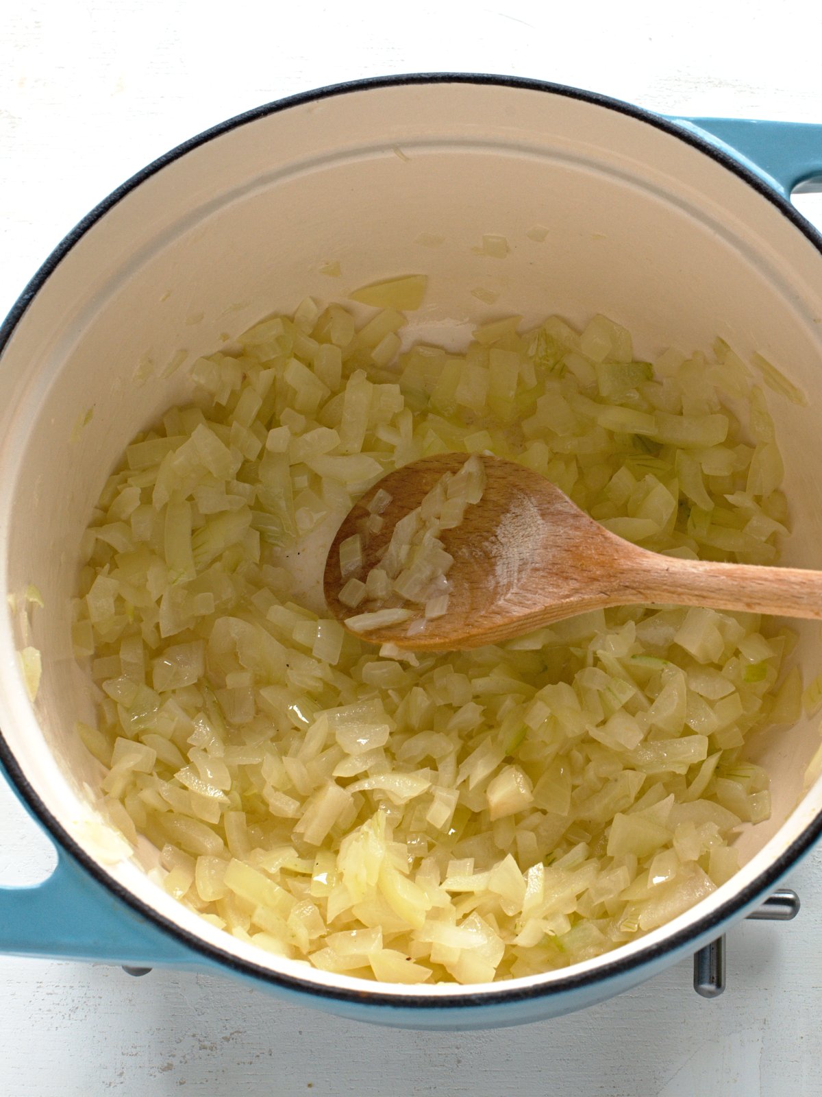 Frying chopped onions in a pot until translucent. 