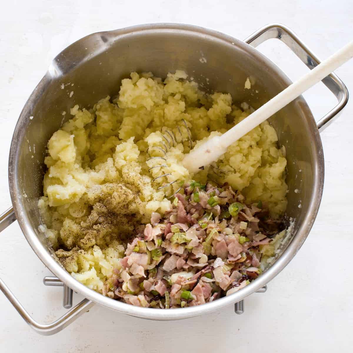 Adding bacon and onions to the mashed potatoes.