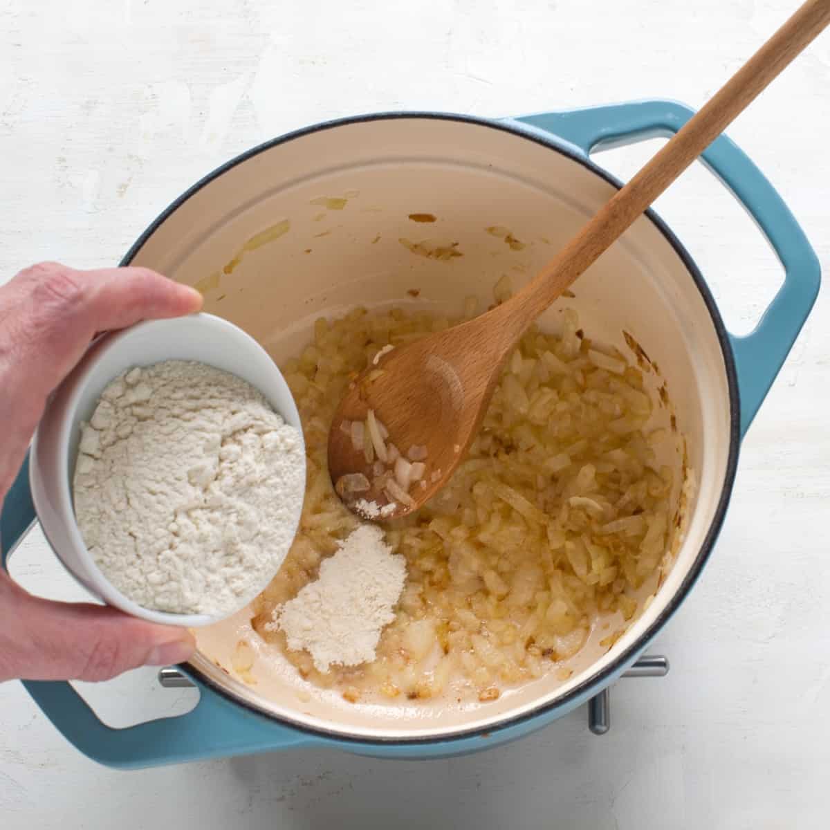 Making onion roux, pouring flour to a pot.