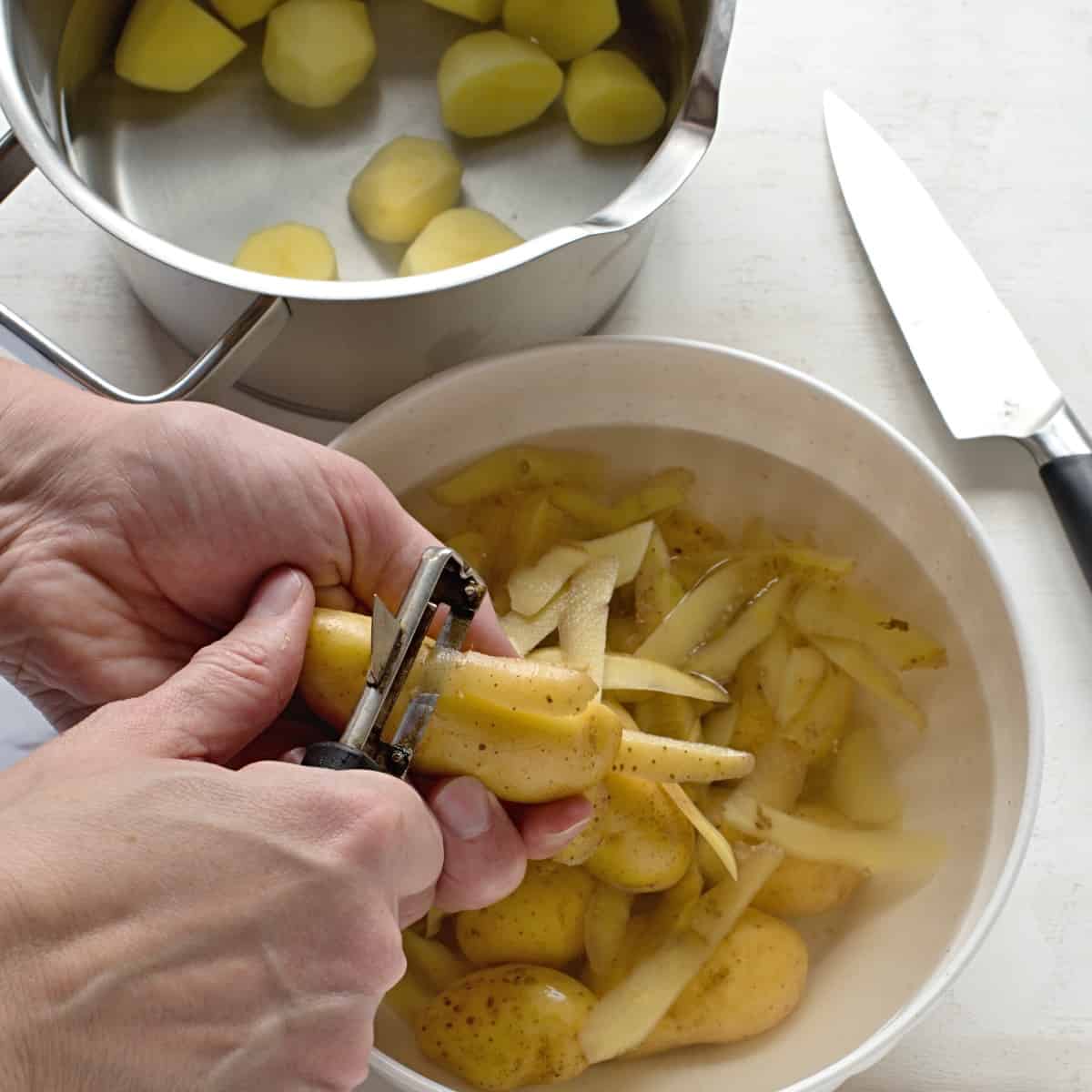 Peeling potatoes and cutting them into pieces.