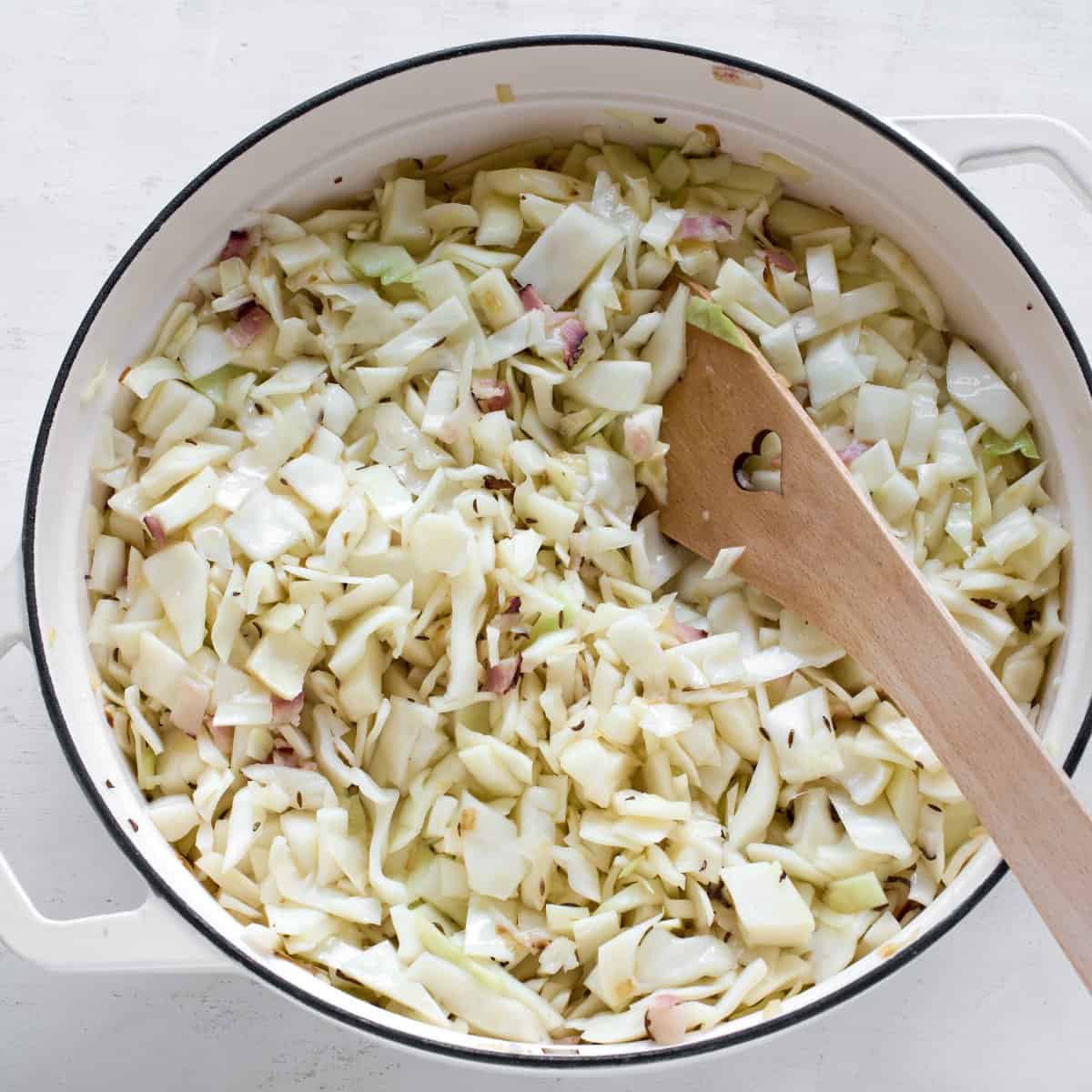 Shredded cabbage with bacon in a pot.