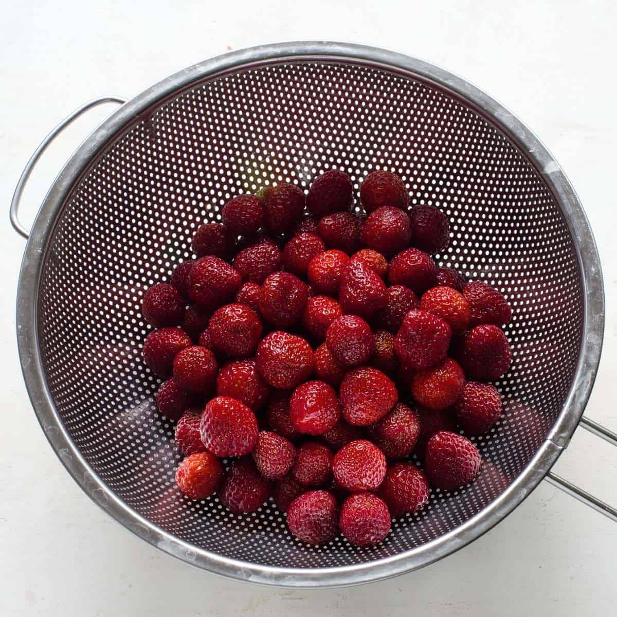 Rinsed and drain strawberries in a colander.