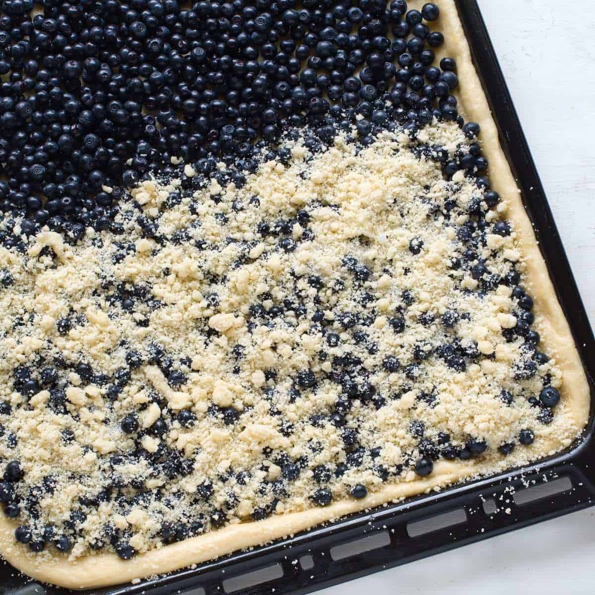 Topping yeasted dough with blueberries and streusel topping.