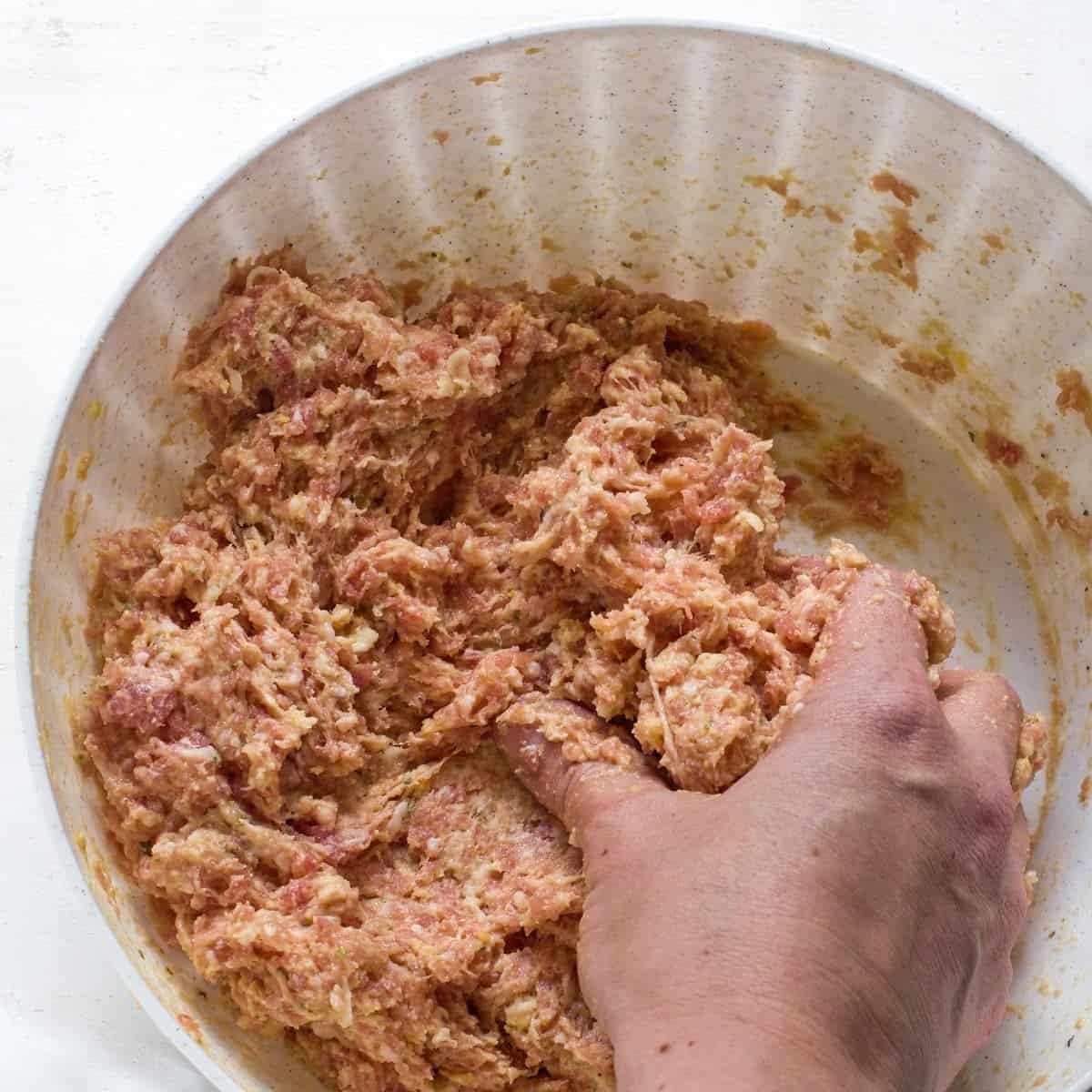 Making meatloaf mixture with a hand.
