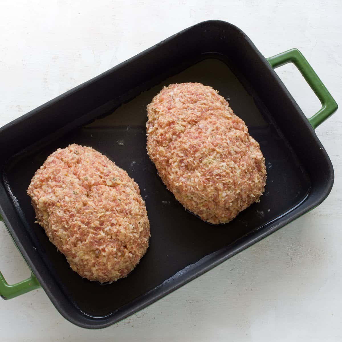 Two pork meatloaves in a baking dish before baking.