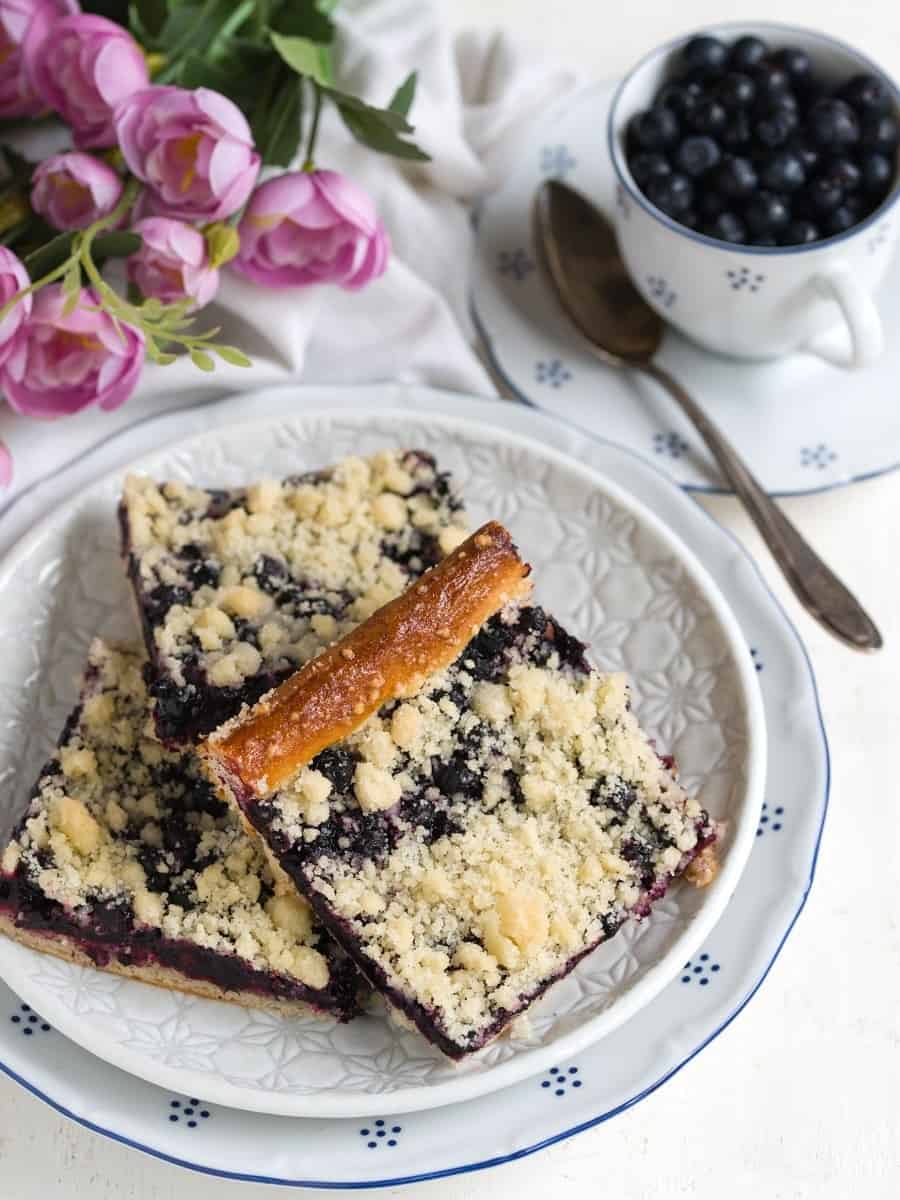 Yeast coffee cake with blueberries, sliced, served on a plate.
