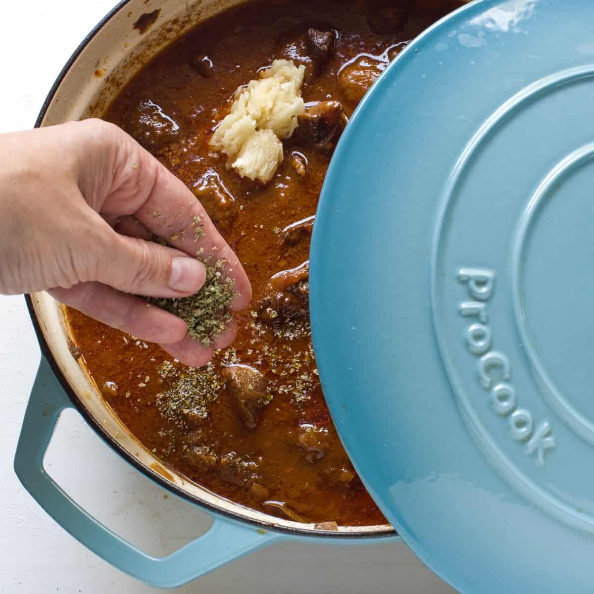 Seasoning goulash in a blue pot.