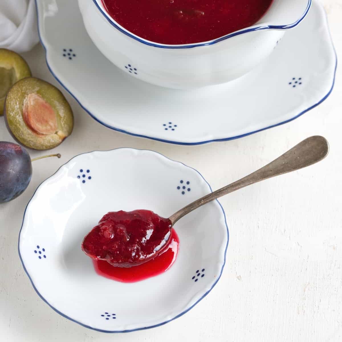 A spoon of plum compote on a small plate.