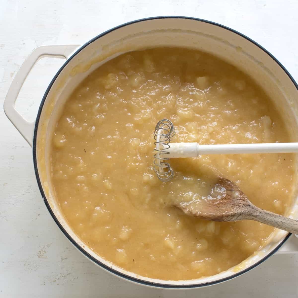 Mashing cooked apples in a pan.