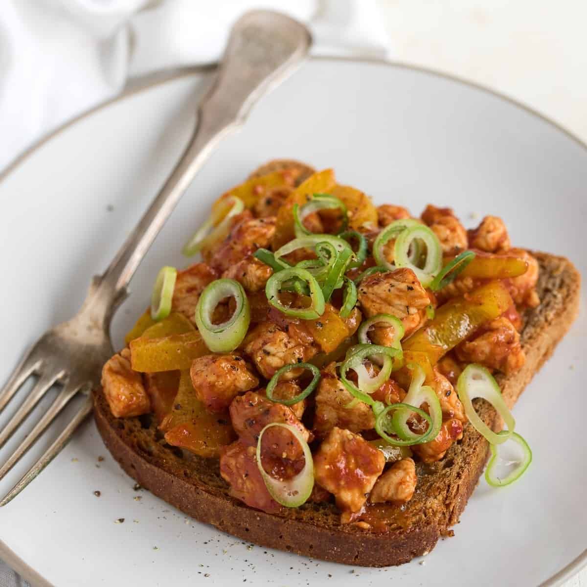 Open faced hot sandwich made with turkey and vegetable mixture, served on a plate with a fork.