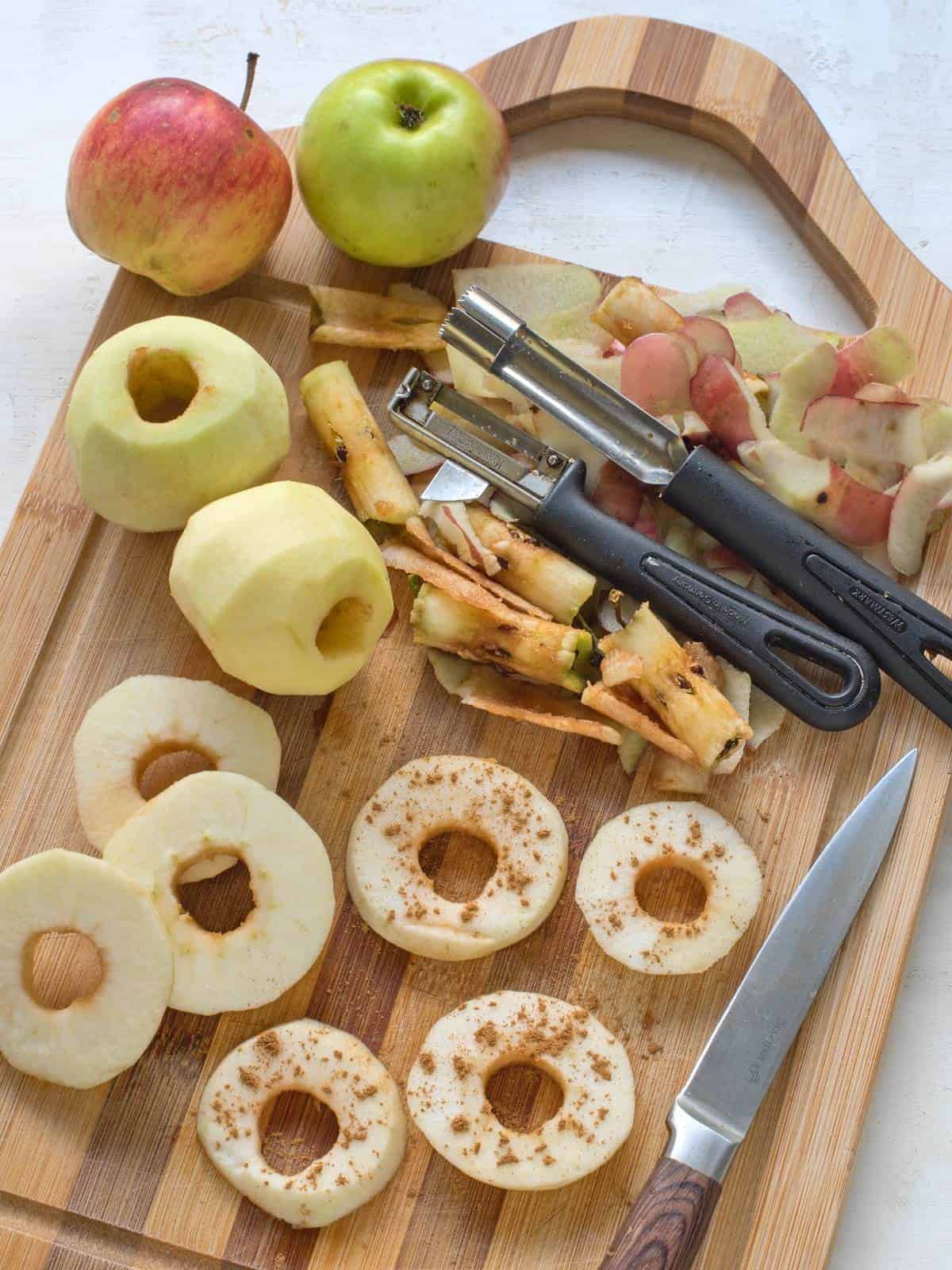Preparing apple circles for frying. Peeling, core removing, slicing in circles, dusting them with cinnamon.