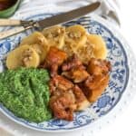 Oven roasted pork belly bites served on a plate with spinach and potato dumplings.