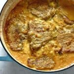 Pork chops in onion gravy, in a skillet.