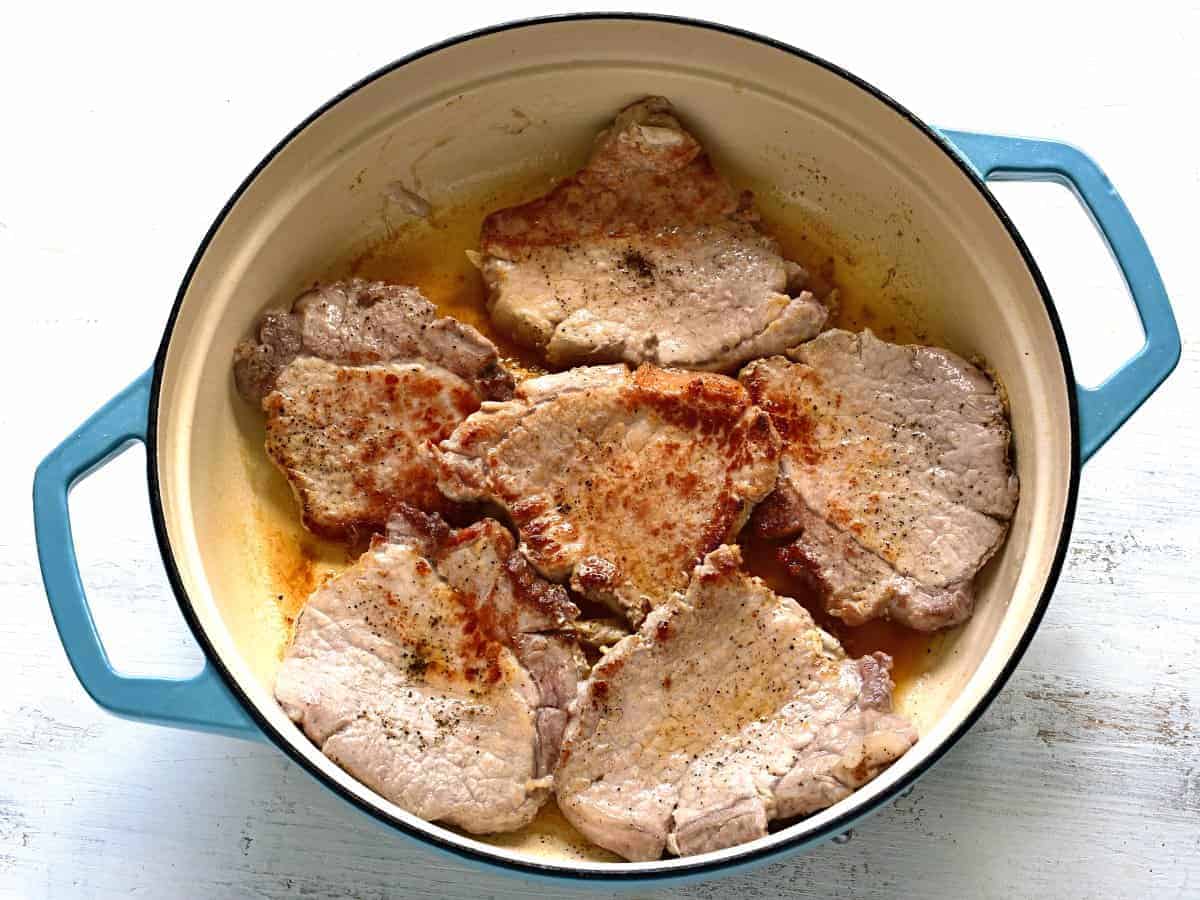 Brown seared pork chops in a skillet.