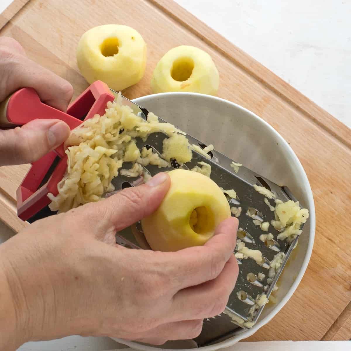 Shredding an apple on hand grater box.