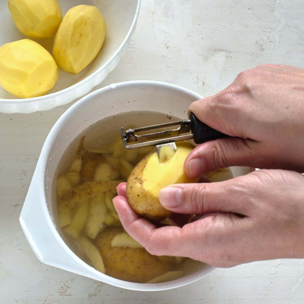 Removing blemishes from the top layer of a potato.