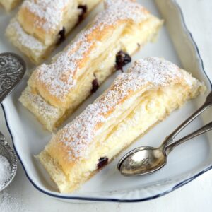 Slices of puff pastry filled with sweet cream cheese mixture, served on a plate.