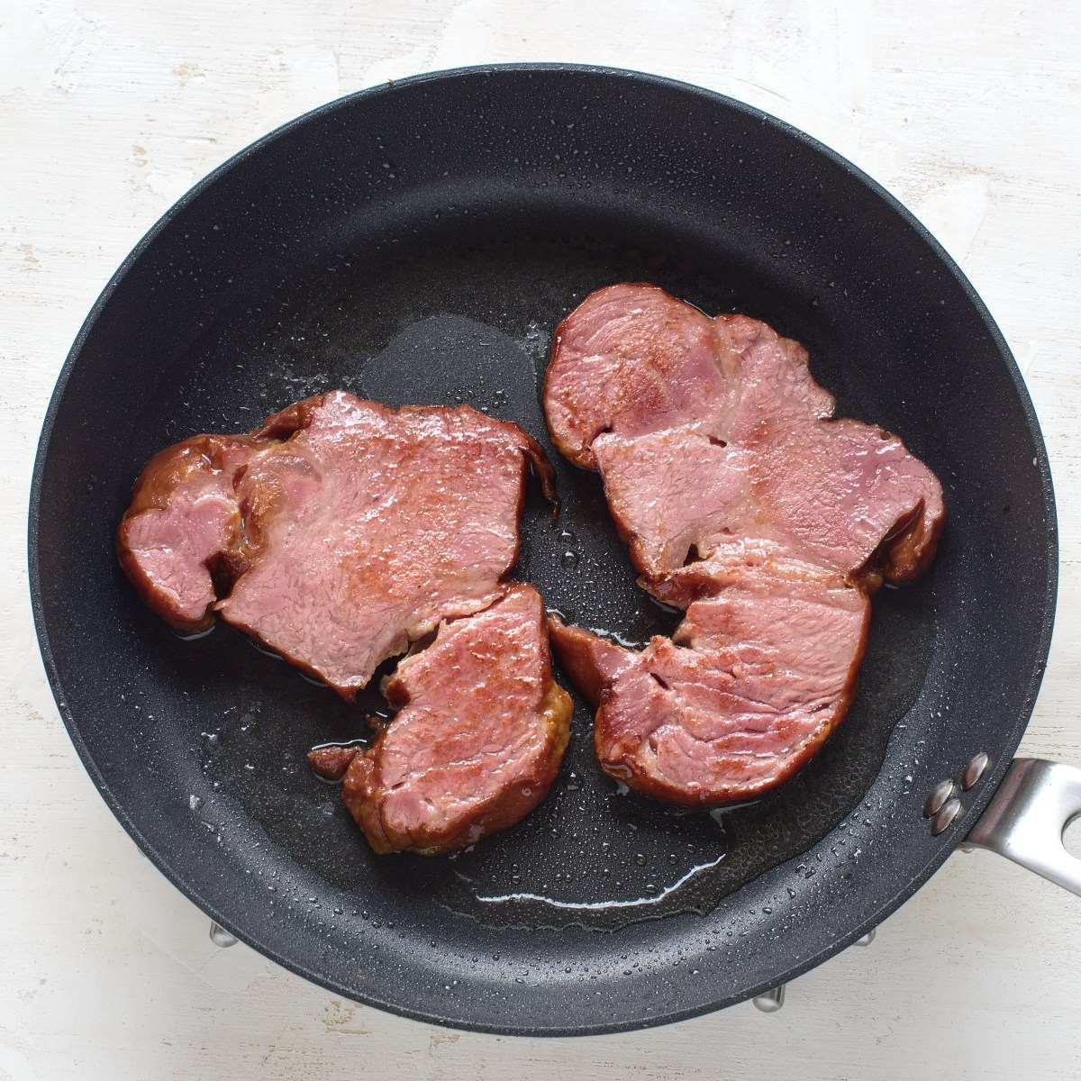Heating smoked pork in a pan.
