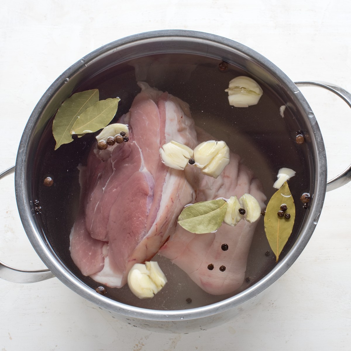 Pork knuckle in a pot of brine, seasoned with spices.