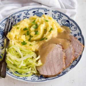 Slices of pork loin roast served with mashed potatoes and coleslaw.