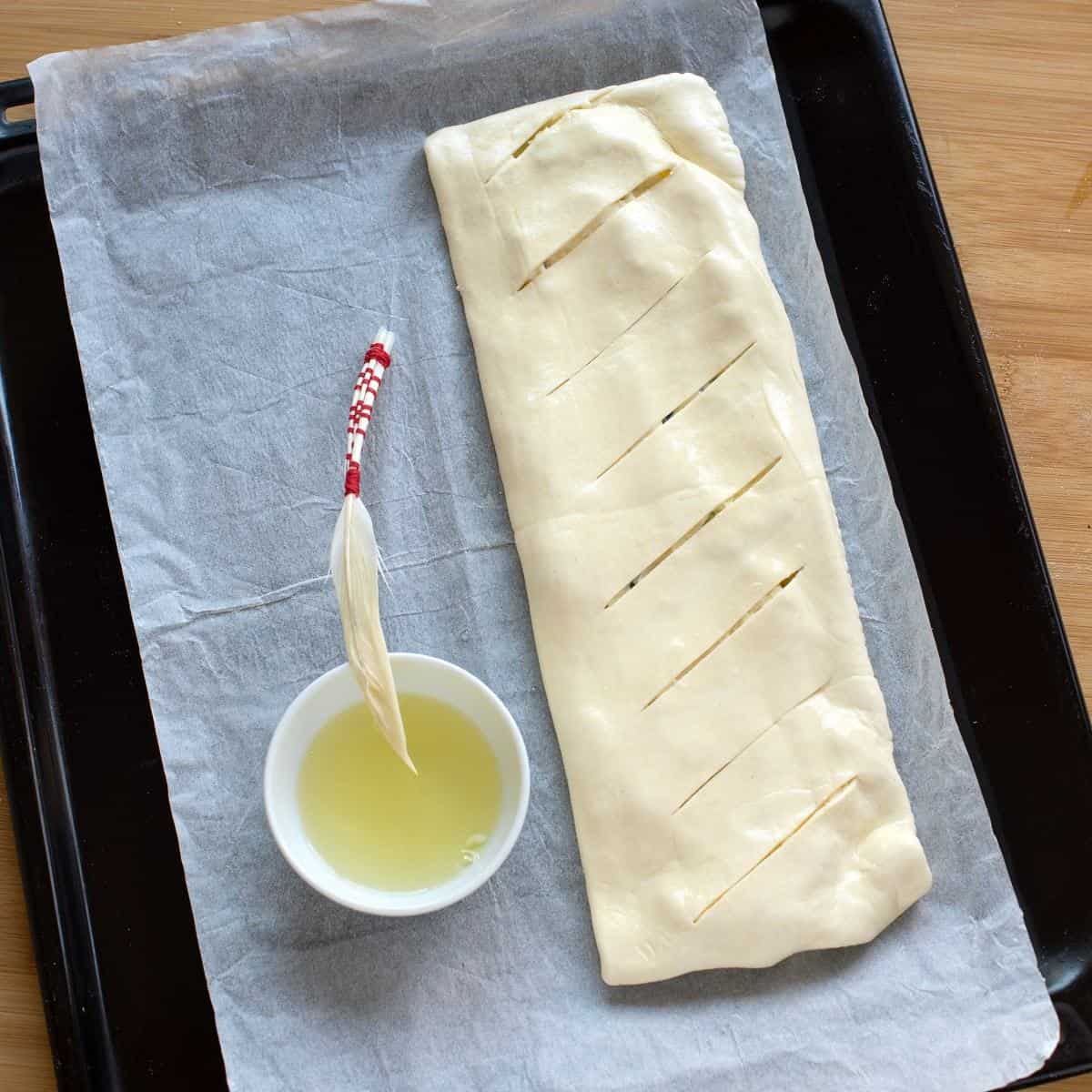 Brushing the surface of puff pastry with egg wash before baking.