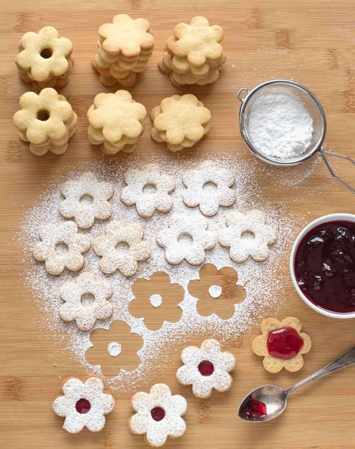 Assembling Linzer cookies dusted with powdered sugar, with red currant jam.