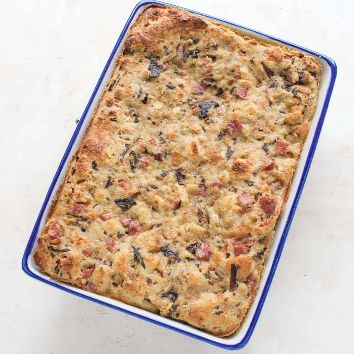 Mushroom bread pudding baked in a square rimmed dish.