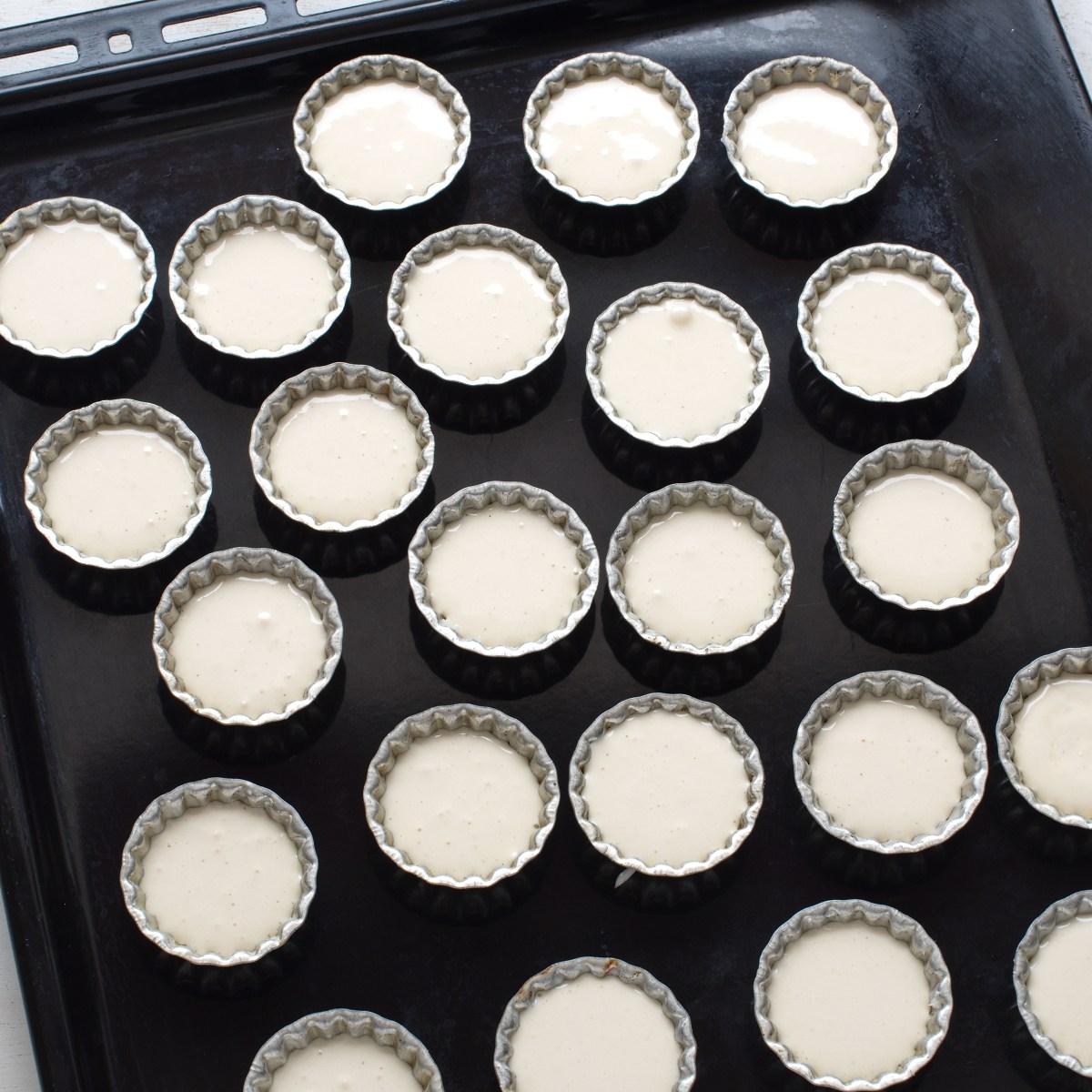 Cookie molds filled with cookie batter, set on a baking tray.