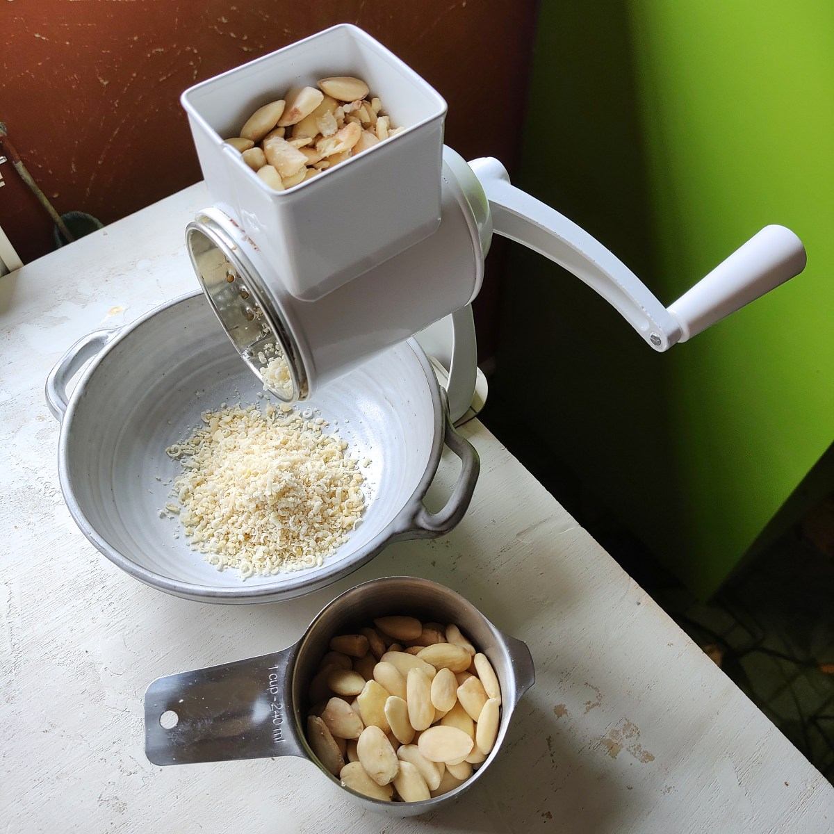 Grinding blanched almonds on a rotary hand grater.