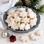 Heavy cream cookies (Czech slehackove cukrovi) coated in powdered sugar, served on a plate.